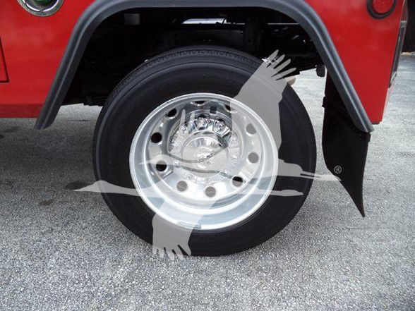 Ram 4500 wheel and fender showing front tire and shiny chrome hubcap with mud flap, red body panel above.