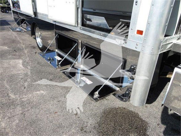 Image of a 2022 International MV truck showing exterior storage compartments under side rail with metal steps and reflective surface.