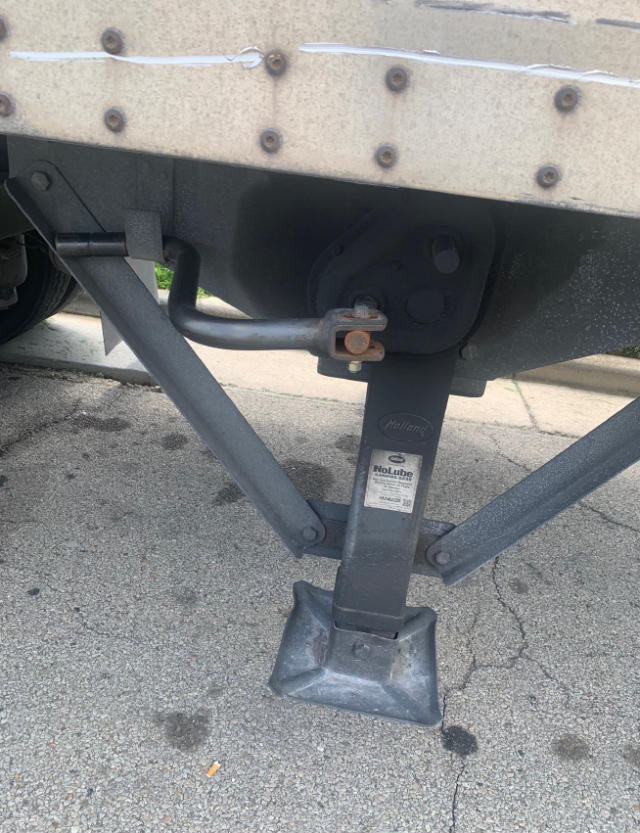 Trailer landing gear and jack stand showing hydraulic leg and stabilizers under a Vanguard VXP trailer.