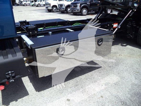Truck bed toolbox mounted on a tow truck chassis with two circular access ports visible on the aluminum toolbox.