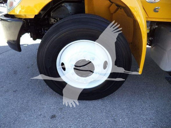 Wheel and tire of a yellow International DURASTAR 4300 truck showing a white hubcap and front fender area.