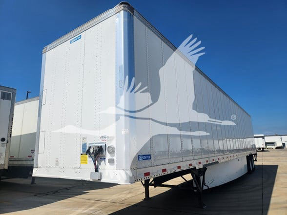 Stoughton trailer with high cube dry van body and white paint. Side view shows riveted panels, front corner with corner post, blue sky background.