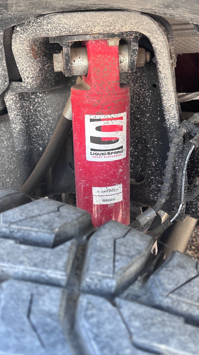 Ford F-550 suspension area with red LiquidSpring Smart Suspension shock absorber and label visible.