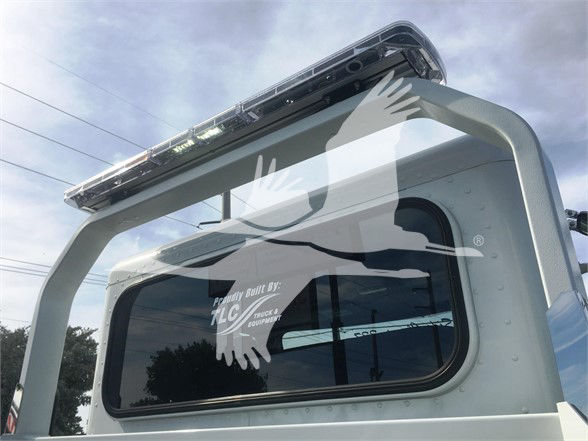 Windowed rear cab area of a 2022 Peterbilt 337 tow truck showing a small window and an emergency light bar on top.