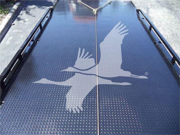 Tow truck trailer deck with a large logo of two soaring birds and a chain tied at the top center.