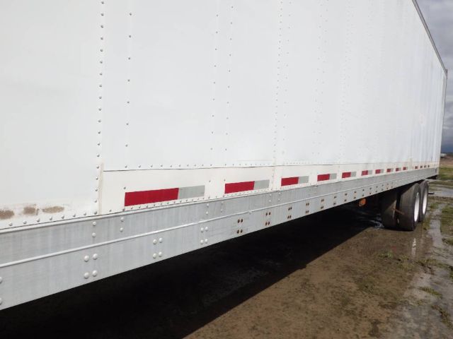 Trailer side showing metal panel with riveted seams and reflective red/white side markers.