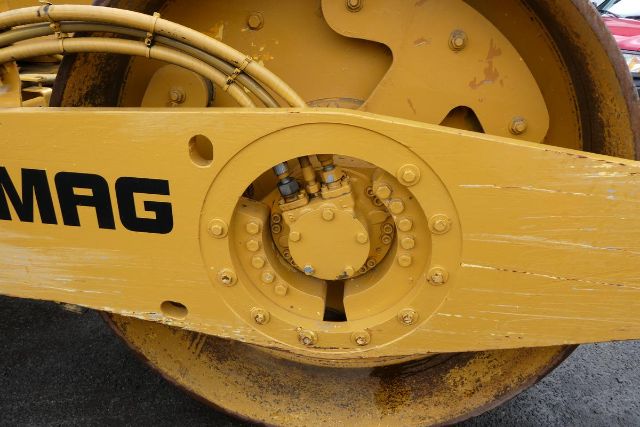 Bomag BW212D-2 drum and hydraulic drive section showing yellow paint with MAG lettering and circular hub bolts.