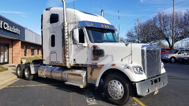 2013 Freightliner Coronado 132 truck in a parking lot with sleeper cab, chrome fuel tanks, and dual rear axles.
