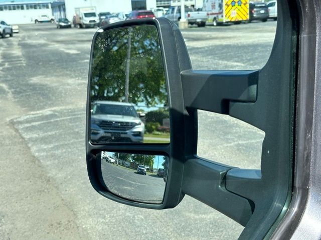 Ford Transit 350 box truck side mirror view with warehouse lot in background.