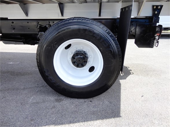 Wheel and undercarriage of a Freightliner M2 106 truck showing white-painted rim and black tire.
