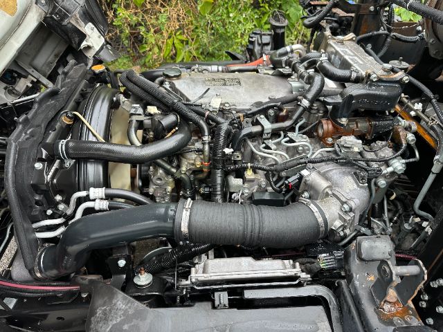 Isuzu NPR-HD engine bay showing turbo intake, hoses, wiring, and accessory components.