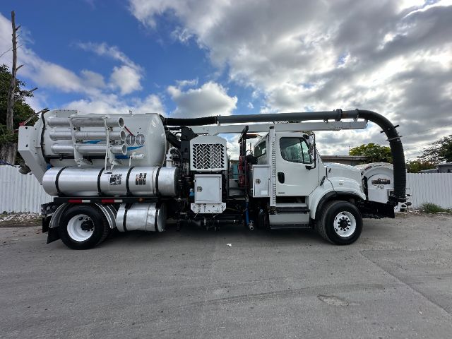 Side view of a 2011 Freightliner M2 vacuum truck with a large hose reel over the cab, vacuum components, and tanks along the chassis.