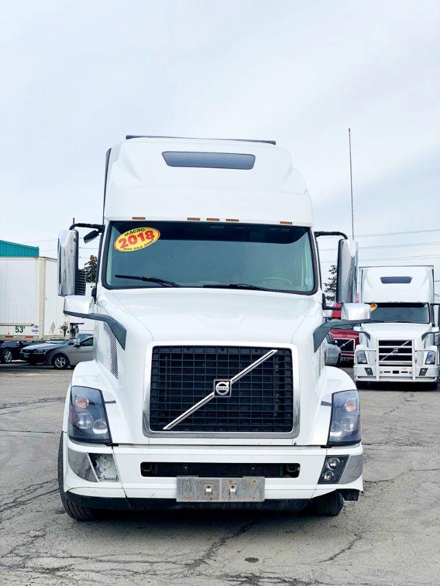 Front view of a white 2018 Volvo VNL 670 conventional sleeper truck with prominent grille and Volvo emblem.