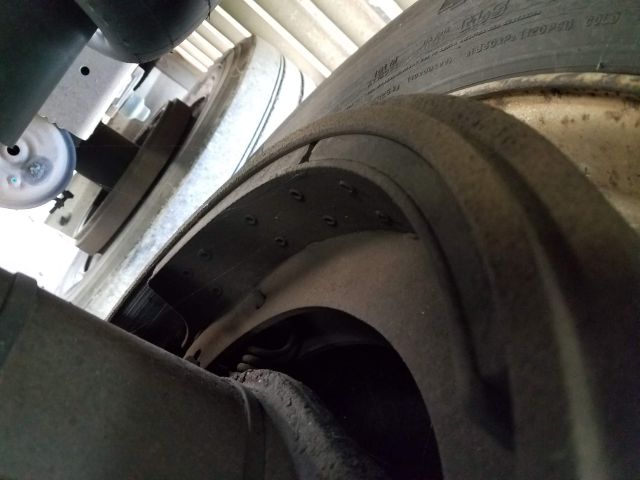 Truck trailer wheel and fender with exposed wheel well; tire tread and riveted metal inner lining visible.