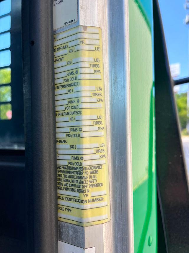 Close-up of a yellow label on a green Peterbilt 348 door post showing vehicle identification and specifications fields such as year, weights, and rims.