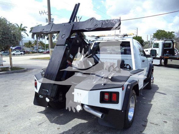 Tow truck rear with hydraulic boom and tow arm, Ram 4500 SLT in white, service body, black hitch mechanism.