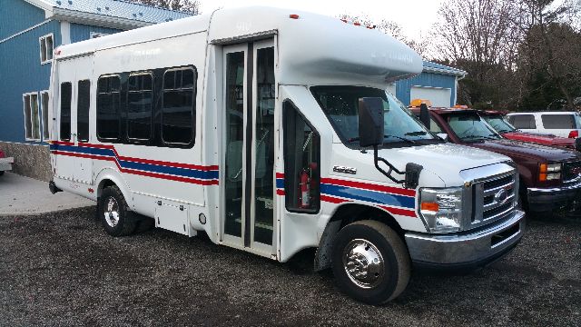 Ford E-450 shuttle bus showing side and front with striped graphics and open door.