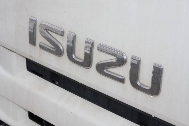 Isuzu emblem on rear of white box truck showing Isuzu branding.