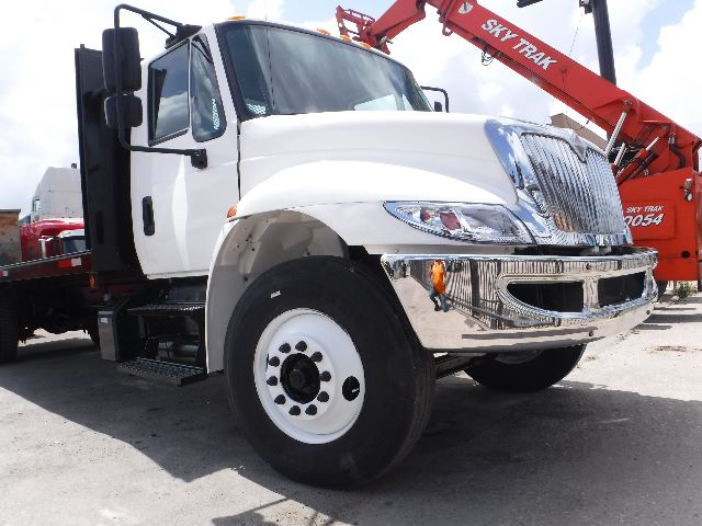 2018 International 4300 flatbed truck front-left view with white cab and chrome bumper.