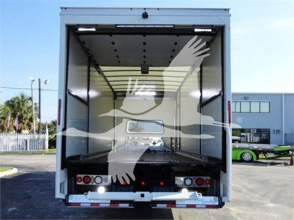 Truck trailer interior viewed from back with empty cargo space and reflective logo overlay. Front cab not visible.