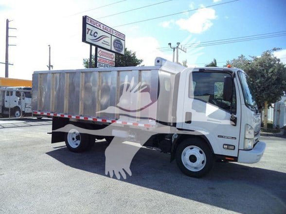 Isuzu NPR HD dump truck in a dealership lot with a large silver dump bed and white cab.