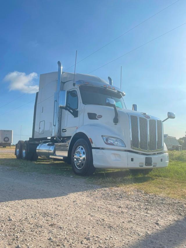 2019 Peterbilt 579 conventional sleeper truck in white, front three-quarter view showing chrome grille, large mirrors, and dual rear axles.