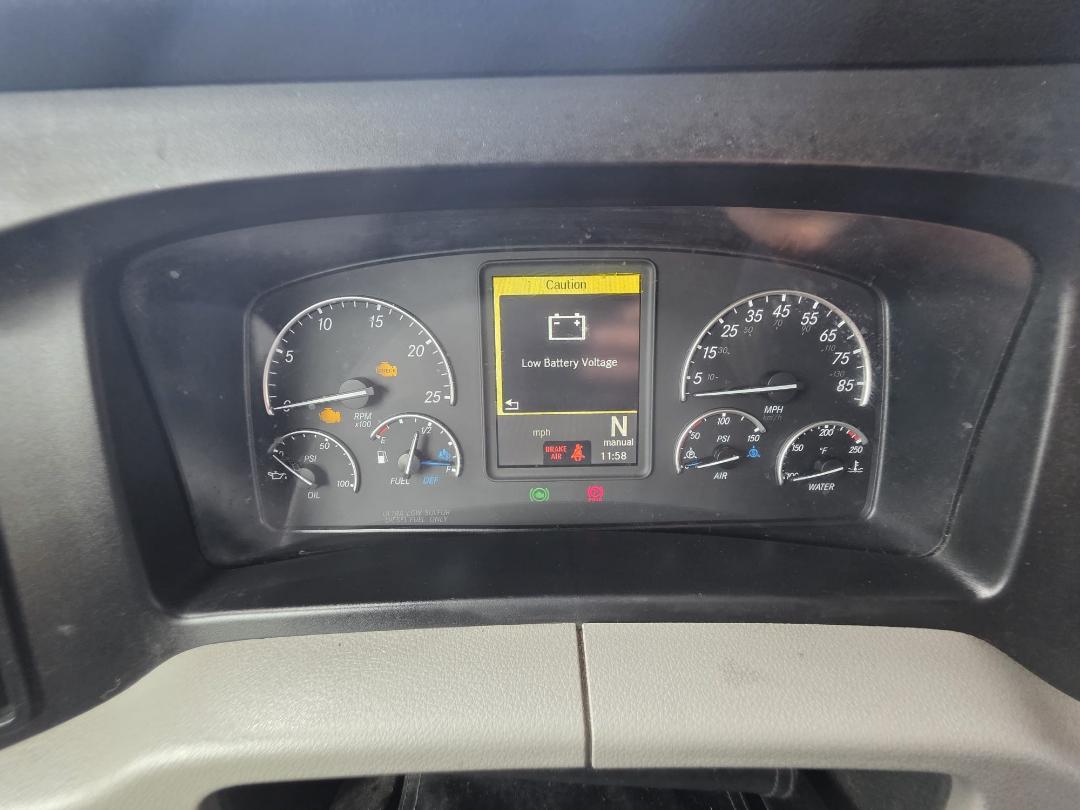 freightliner cascadia dash cluster showing low battery voltage warning on center display, with gauges for RPM, speed, fuel, oil, air, and water.