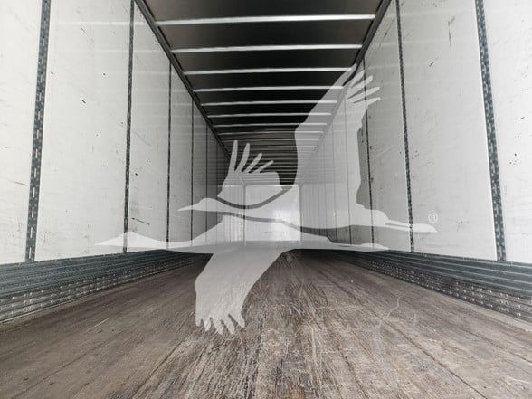 Trailer interior with metal side walls and wooden floor, empty cargo space.