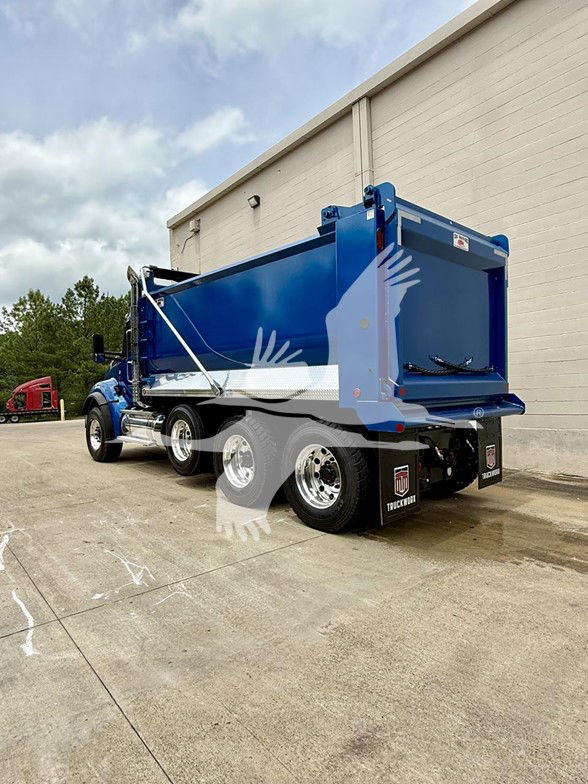 Kenworth T880 dump truck in blue shown from rear 3/4 view with dump body elevated, side chrome exhaust, dual rear axles.