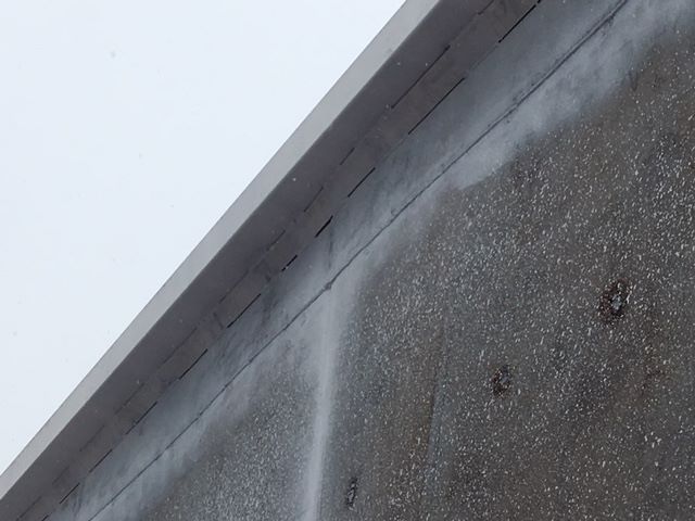 Concrete trailer wall with textured surface and edge of metallic roof trim visible.