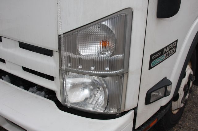 Isuzu NPR-HD box truck front corner showing headlight cluster and ECO MAX badge on the fender.