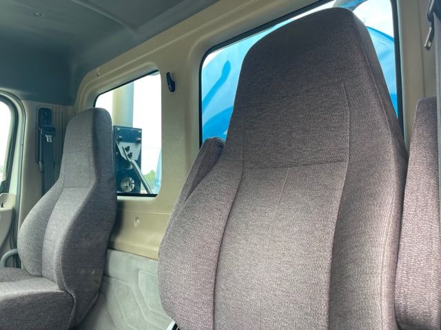 Truck interior showing seating and cabin window. Grey fabric seats with beige interior walls.