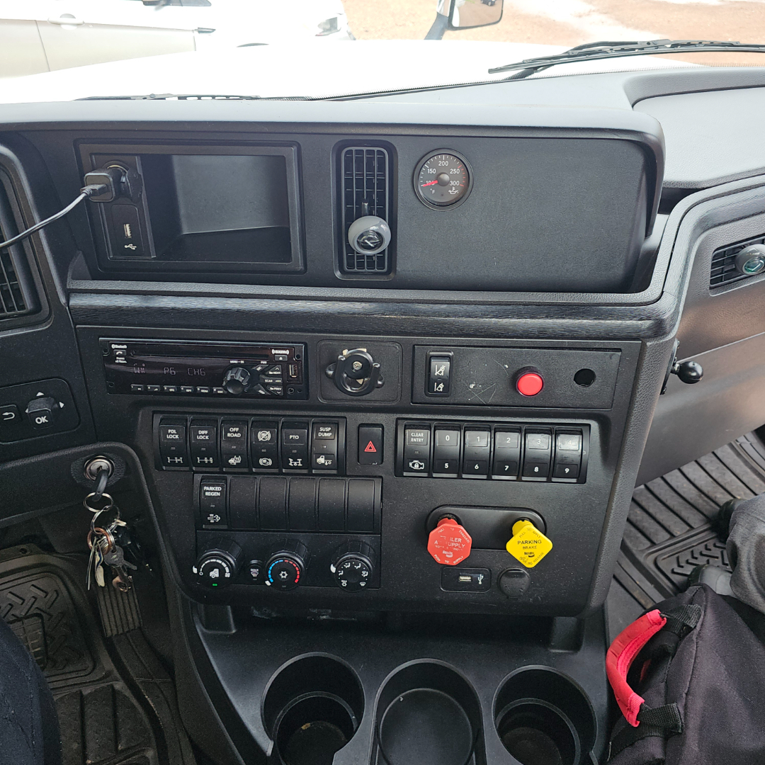 Dashboard of a 2020 International LT truck showing various controls, gauges, and ignition area with red and yellow switches.
