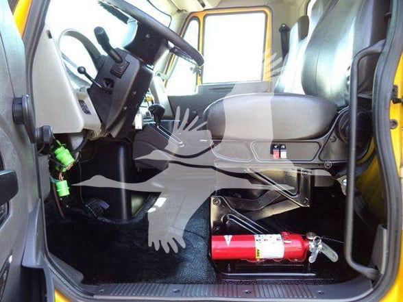 Interior cab of a 2019 International DURASTAR 4300 truck showing steering wheel, driver seat, and a red fire extinguisher mounted under the dashboard area.