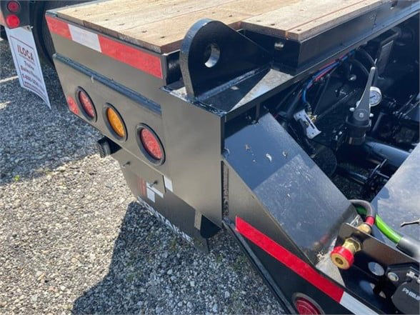 Lowboy trailer rear corner showing toolbox with three circular lights and platform decking, Fontaine 55 ton steel roller paver black lowboy captioned area.