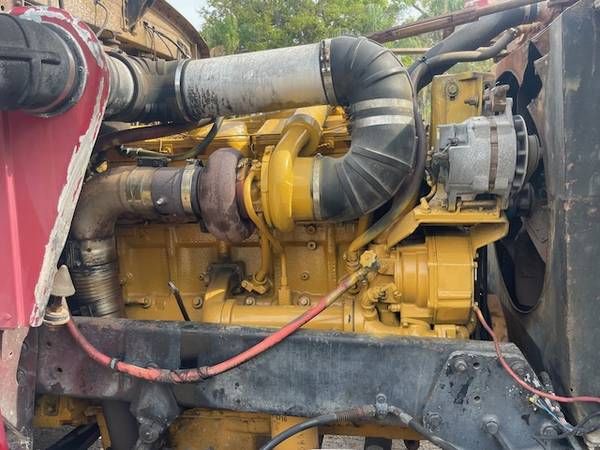 Truck engine bay with a yellow diesel engine, large turbocharger, hoses, and fan visible.