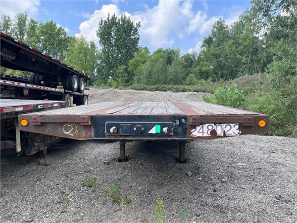 Dynaweld steel stepdeck trailer rear view showing deck surface and bumper with small tag numbers.