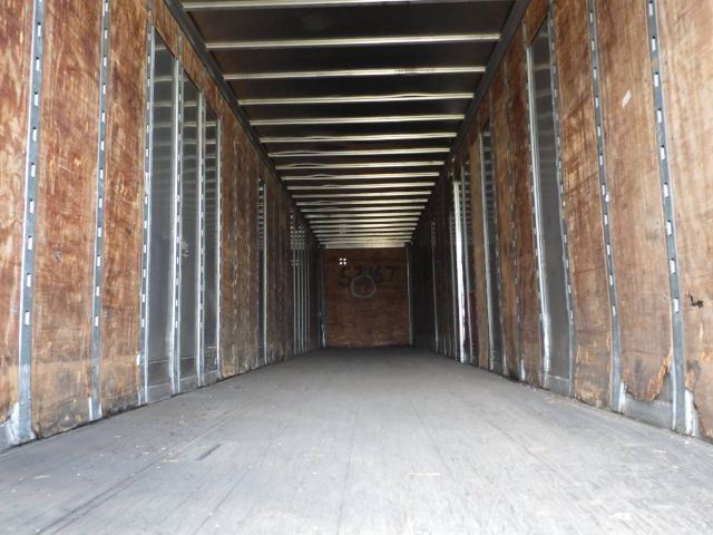 Inside of a Fruehauf storage/short haul trailer with wooden walls and metal frame rails, empty cargo area.