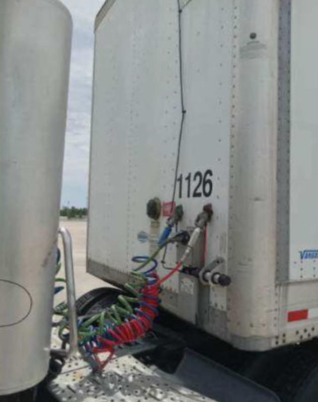 Trailer rear with Vangua rd VXP auxiliary connections and coiled air hoses visible on the back of a silver utility trailer.