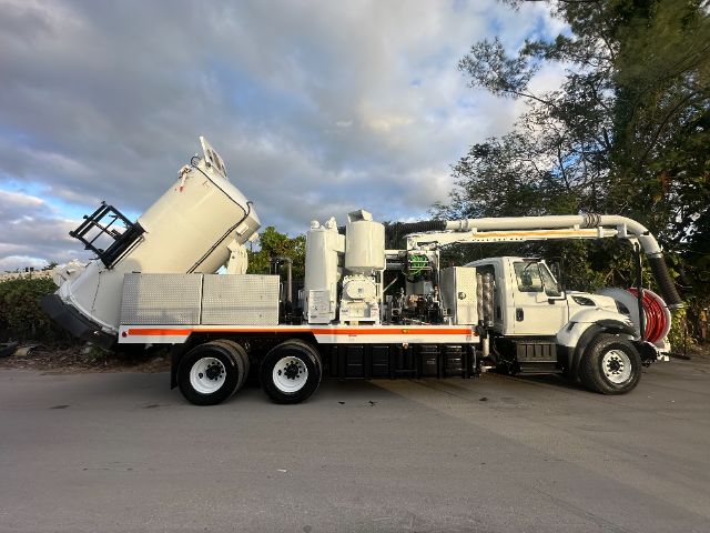 International 7400 vacuum truck with large rear mixer and hose reel system, white with orange reflective stripe, side view.