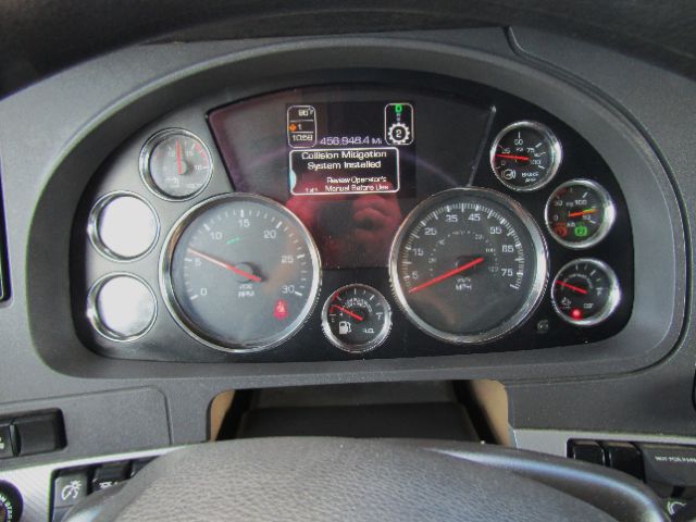 Dashboard of a 2020 Kenworth T680 showing multiple gauges and a central display with text that reads 'Collision Mitigation System installed' and other diagnostic prompts.