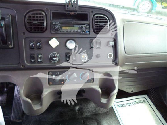 Cockpit view of a Freightliner M2 106 interior with dashboard controls and cup holders visible.