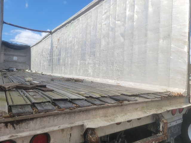 Back of a Warren WHDT48x102-2-AS walking floor trailer with metal siding and planked bed deck.
