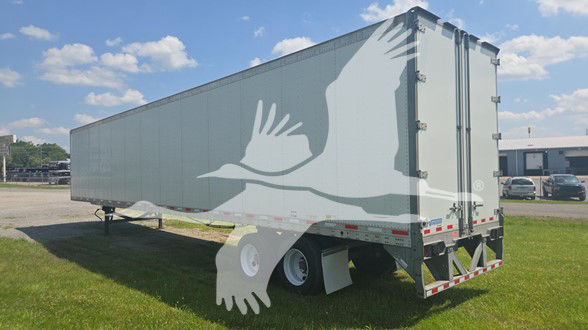 Trailer side and rear view showing closed GVW-dress decorated with large flying bird graphic and dual rear doors.