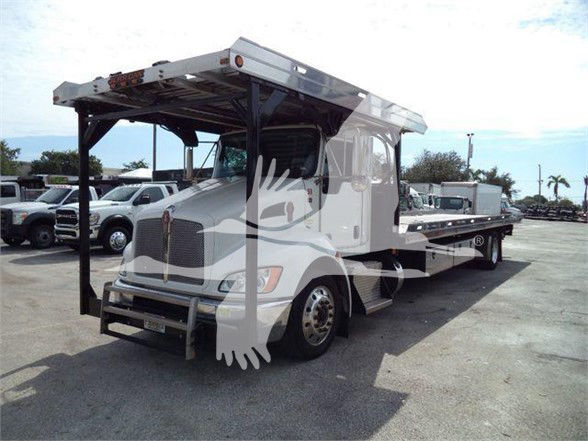 Kenworth T370 tow truck with a flatbed and a gooseneck-style service body. Visible text on sticker near front grille and on side shows generic truck branding; no legible model or tag readable clearly.