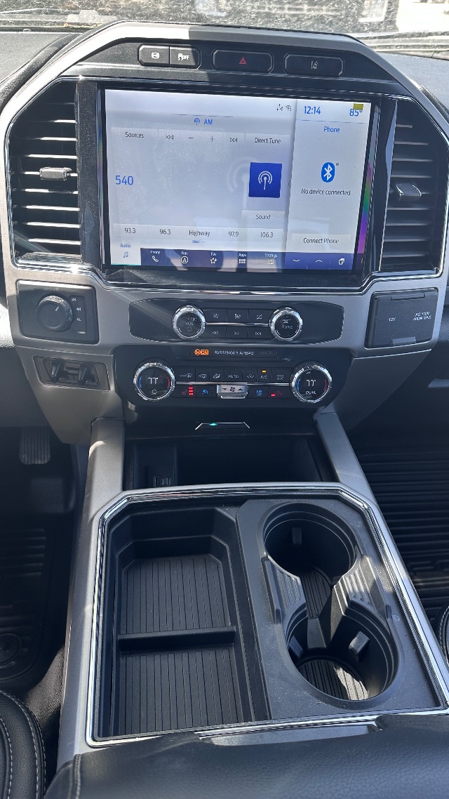 Ford F-550 interior center console with large touchscreen display showing infotainment system, climate control dials, and cup holders.