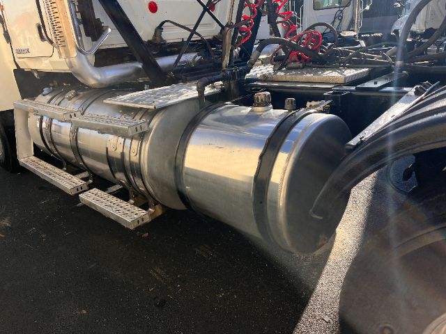 Truck fuel tank and side components of a 2013 Mack CHU613 Pinnacle tractor showing a cylindrical aluminum fuel tank with mounting bands and steps nearby.