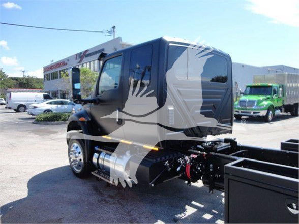 New International MV tow truck cab view showing side fuel tank, chassis, and wheel. Visible text: none legible on labels.