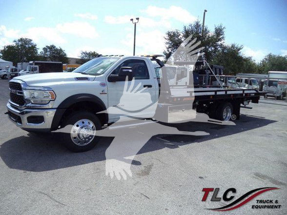2024 Ram 5500 SLT tow truck with flatbed, white cab, dual rear wheels, side view showing front grille and RAM badge.