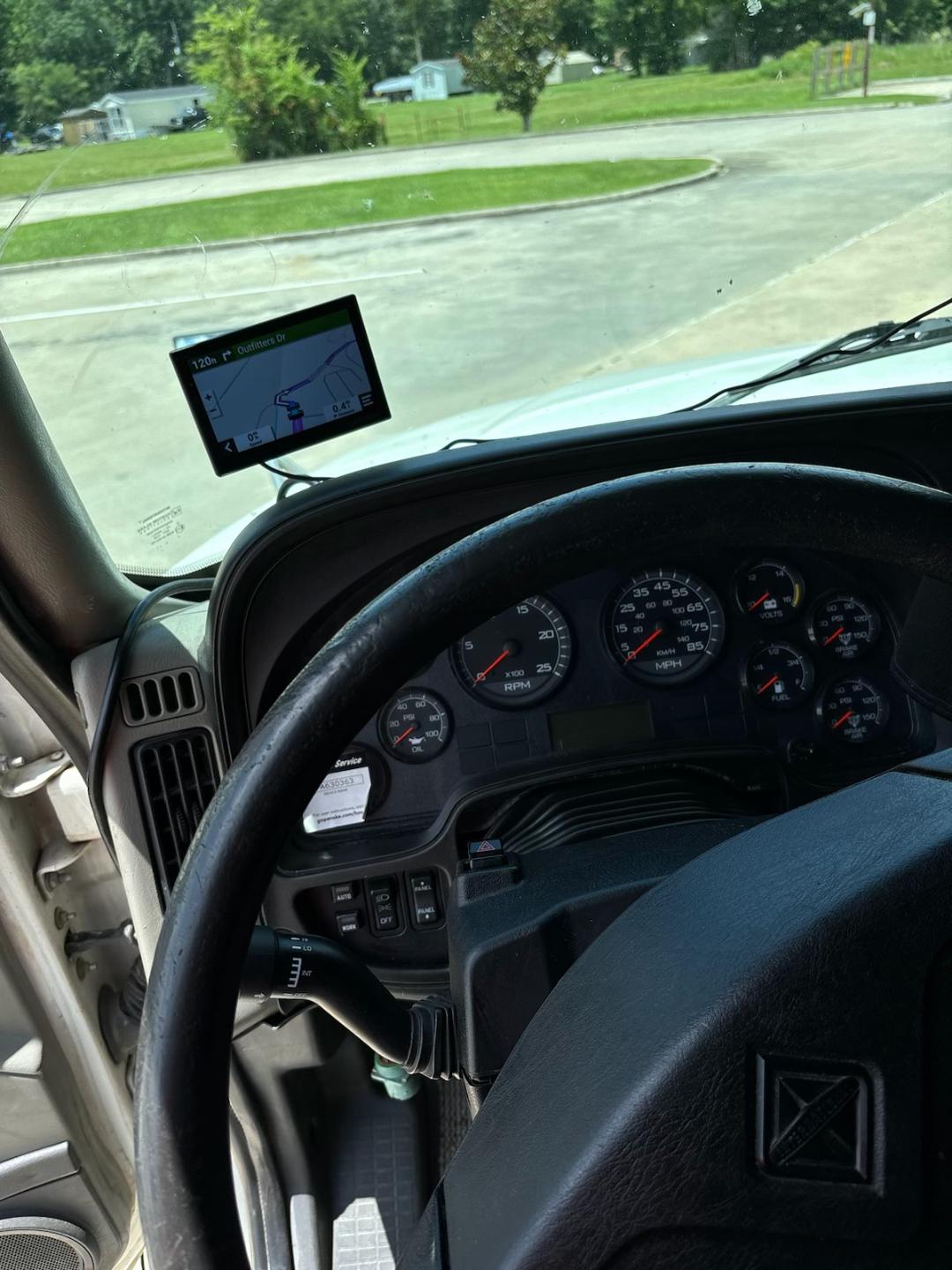 Interior of a 2016 International ProStar cab showing dashboard gauges, steering wheel, and a mounted GPS device near the windshield.